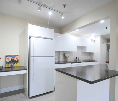 A white refrigerator stands in a kitchen with a black counter.