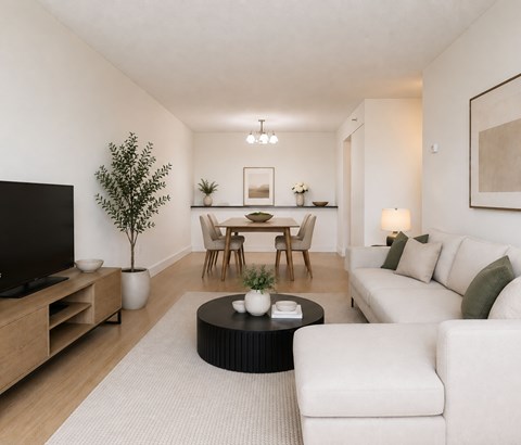 A living room with a white couch, a black coffee table, and a wooden entertainment unit.