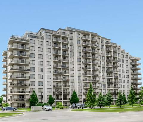 A large apartment building with balconies and trees in front.