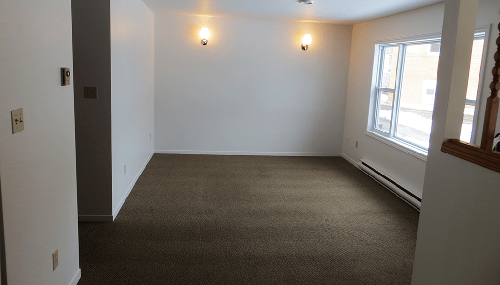 an empty living room with a large window and white walls