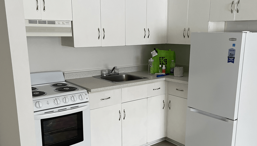 a small kitchen with white cabinets and a sink and a refrigerator