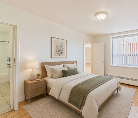 A bedroom with a bed, nightstand, and lamp.