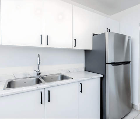 A kitchen with white cabinets and a stainless steel refrigerator.