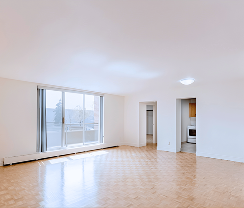 A spacious room with a large window and a door leading to another room.