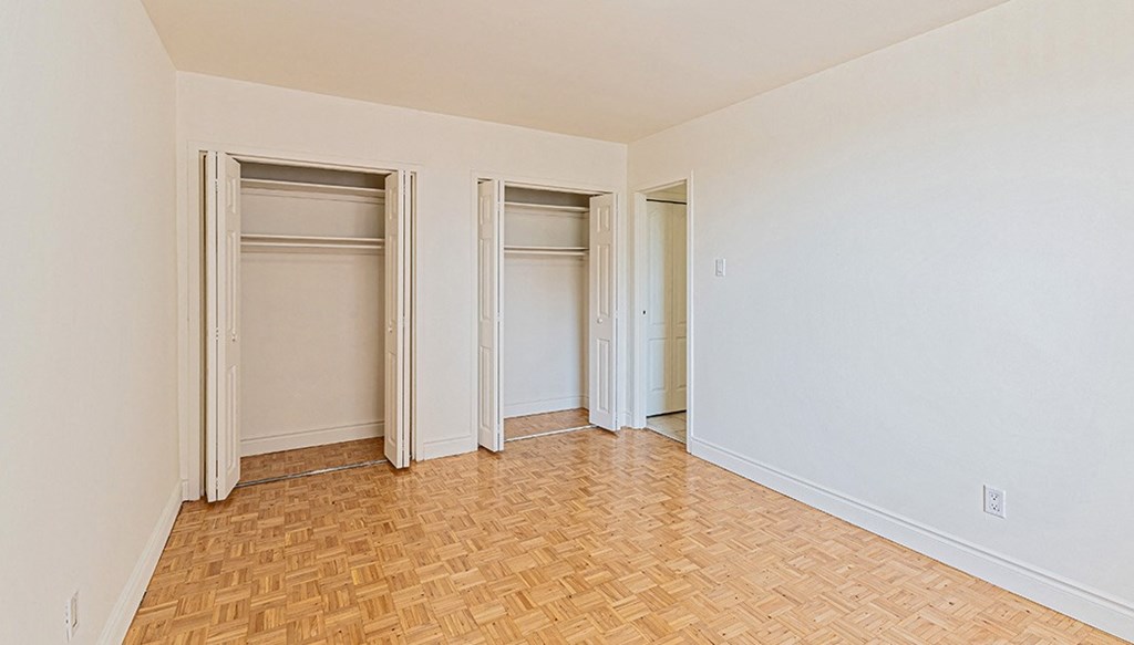 an empty living room with three sliding closet doors