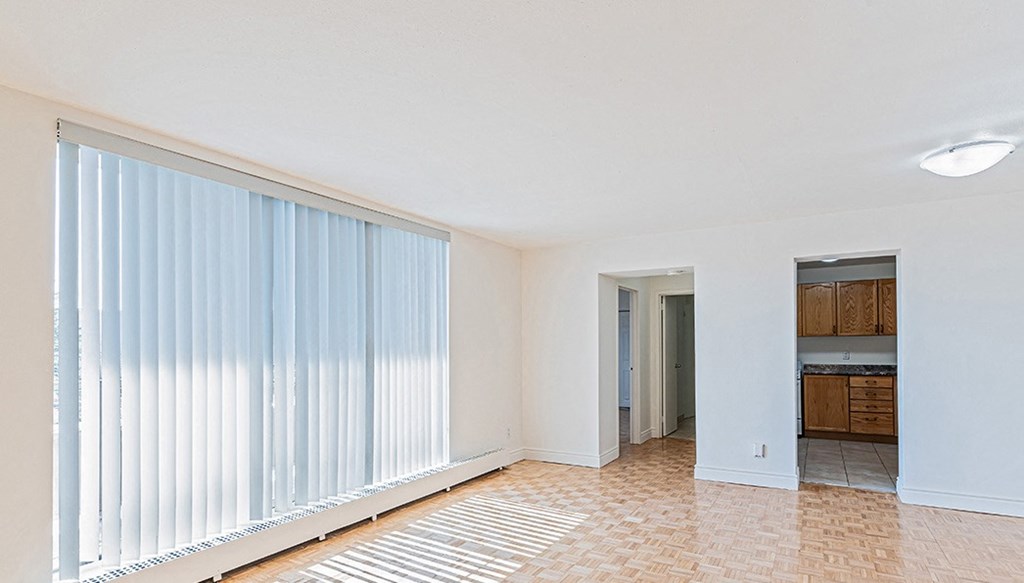 an empty living room with a large window with white blinds