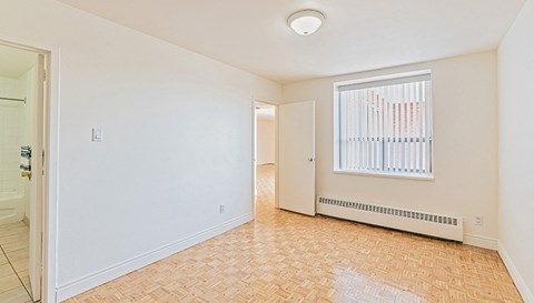 an empty living room with a window and a door to a hallway