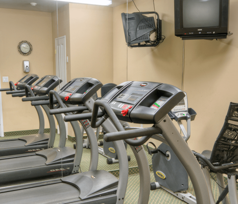 A gym with treadmills and a television mounted on the wall.