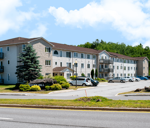 A large apartment complex with a parking lot in front.