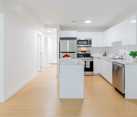 A modern kitchen with white cabinets and stainless steel appliances.