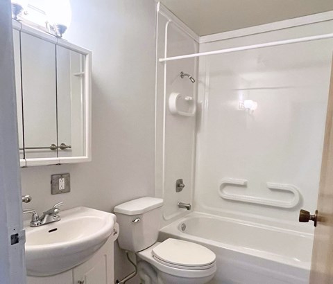A white bathroom with a toilet, sink, and bathtub.