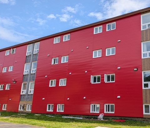 A red building with white windows and a blue sky in the background.