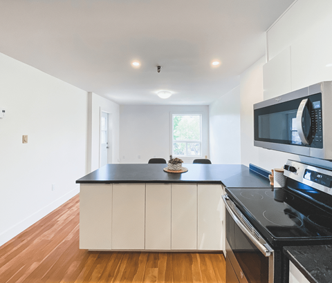 A kitchen with white cabinets and black countertops.