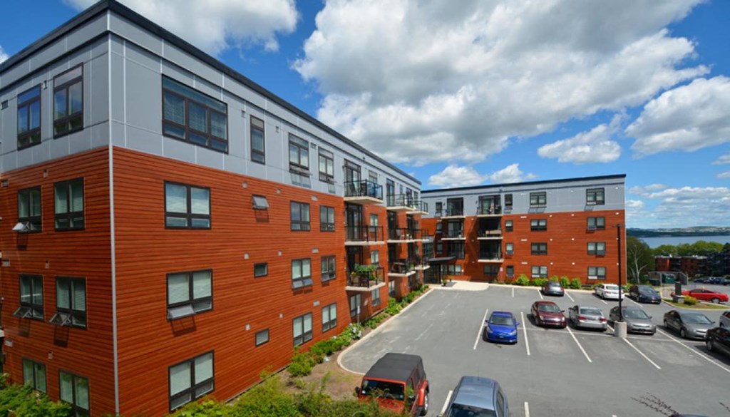 a view of an apartment complex with cars in a parking lot