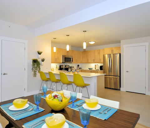 A modern kitchen with a dining table set for two.