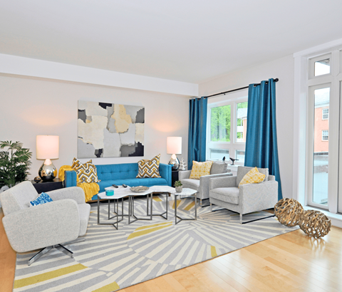A living room with a grey couch, a grey armchair, a coffee table, and a rug with a striped pattern.
