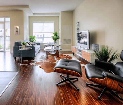 A living room with a black leather chair and a wooden floor.