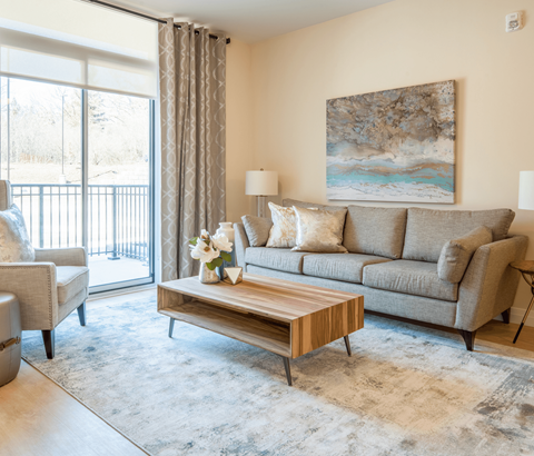A living room with a grey couch, a wooden coffee table, and a painting on the wall.