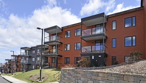 a row of modern apartments with balconies and a stone retaining wall