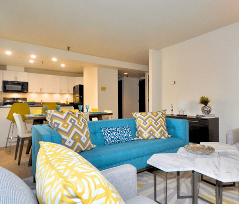A blue couch with yellow and white pillows sits in a modern living room.