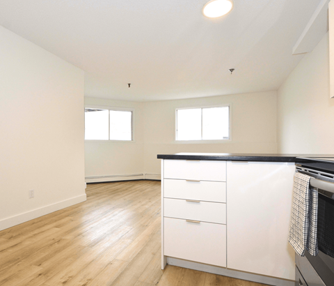 A kitchen with white cabinets and a black countertop.