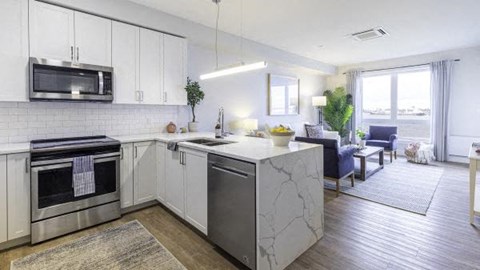 A modern kitchen with white cabinets and a marble island.