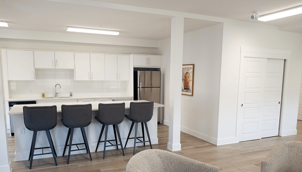 a kitchen with white cabinets and a bar with stools