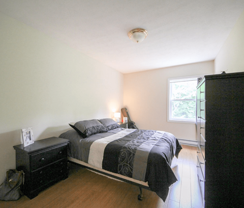 A bedroom with a bed, nightstand, and window.