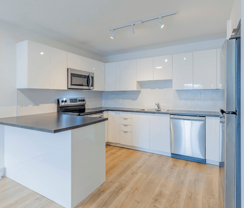 A modern kitchen with white cabinets and a black countertop.