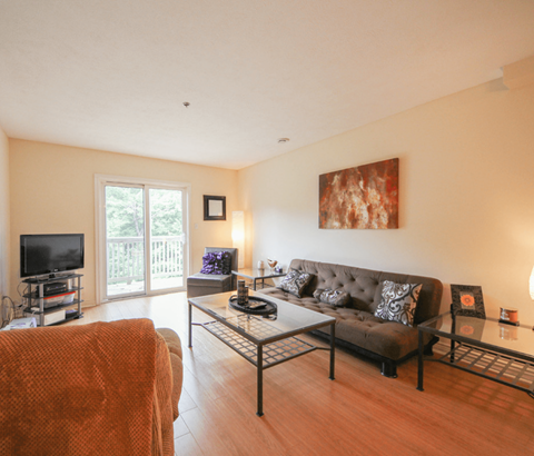 A living room with a brown couch and a glass coffee table.
