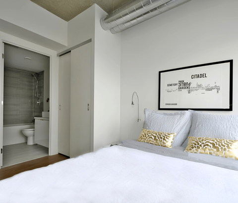 A bedroom with a bed, pillows, and a Citadel poster on the wall.