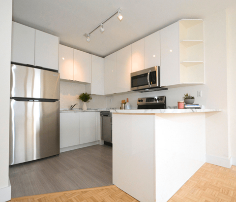 A kitchen with white cabinets and a stainless steel refrigerator.