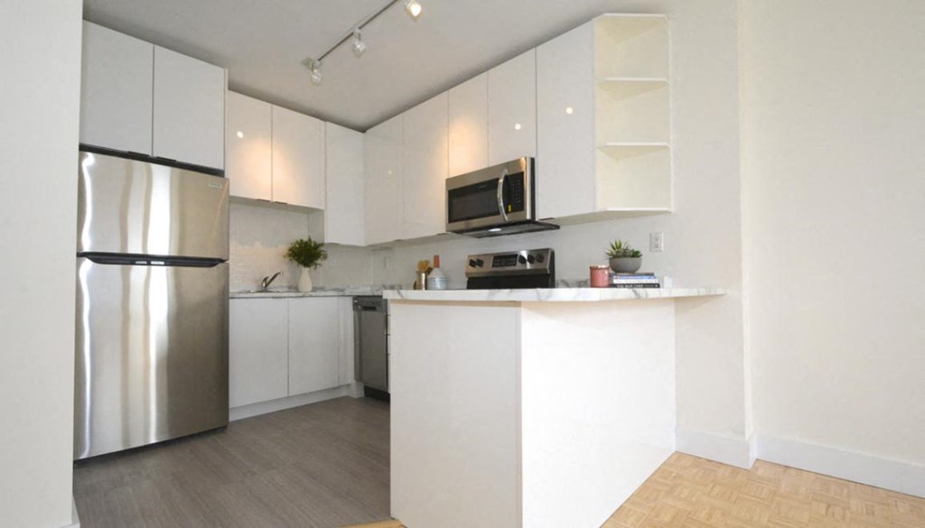 a kitchen with white cabinets and a stainless steel refrigerator