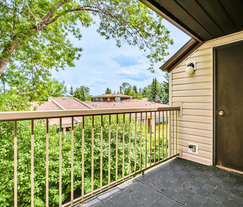 A balcony with a view of a house and trees.