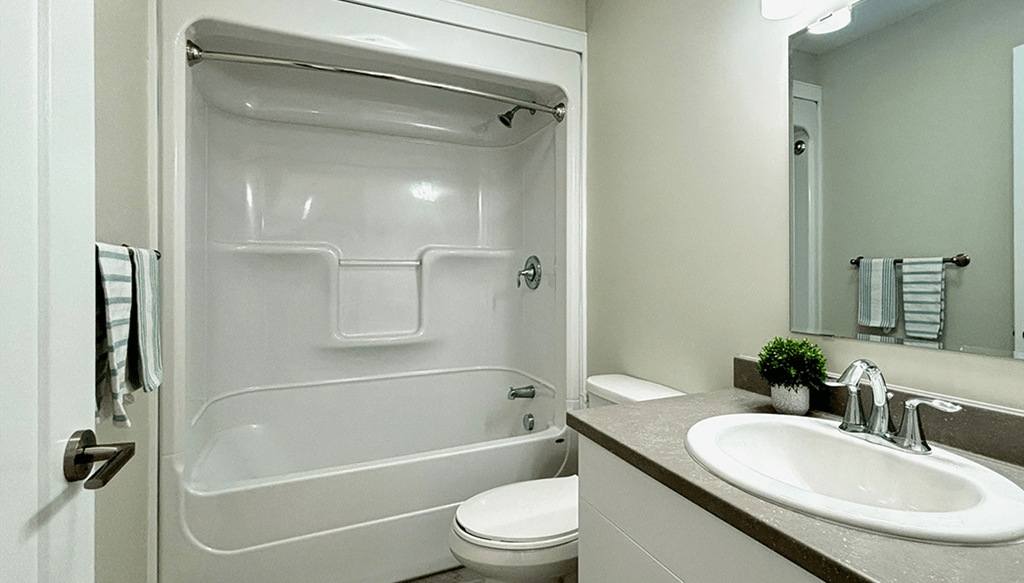 A white bathroom with a toilet, sink, and a glass shower stall.