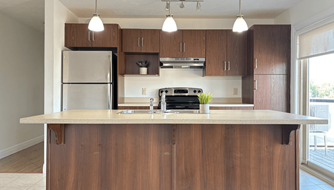 A kitchen with a refrigerator, oven, and sink.
