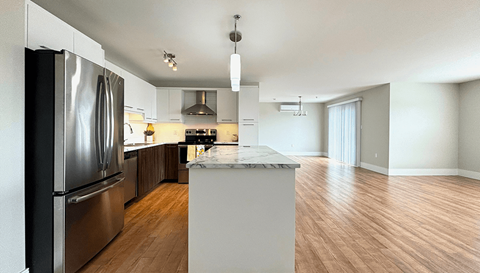 A modern kitchen with a stainless steel refrigerator and a marble island.