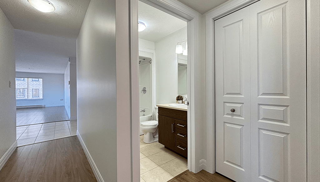 A white bathroom with a toilet, sink, and a white door.