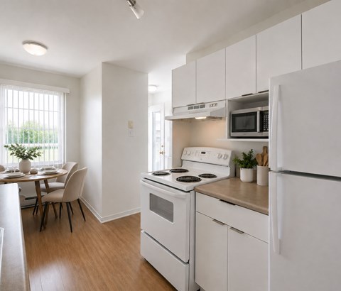 A white kitchen with a stove, refrigerator, and dining table.