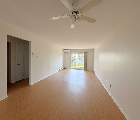 A room with a ceiling fan and wooden flooring.