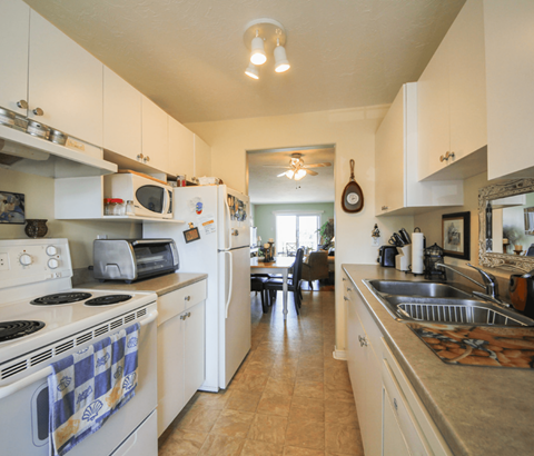 A kitchen with white cabinets and a checkered towel on the stove.