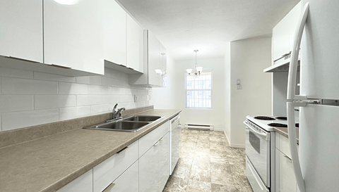 A kitchen with white cabinets and a tiled backsplash.