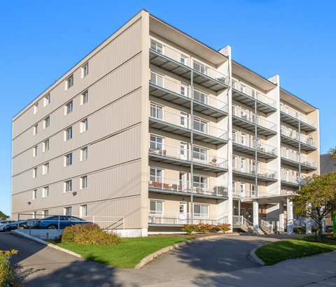 A large apartment building with a parking lot in front.