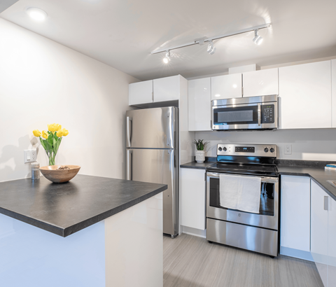 A modern kitchen with a stainless steel refrigerator, oven, and microwave.