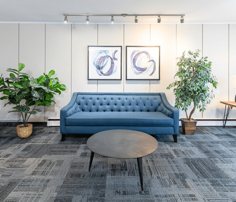 A blue sofa with a grey coffee table in front of it.