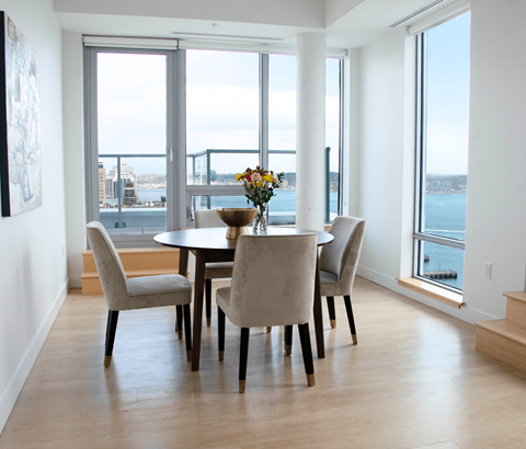 A dining room with a table and chairs and a view of the water.