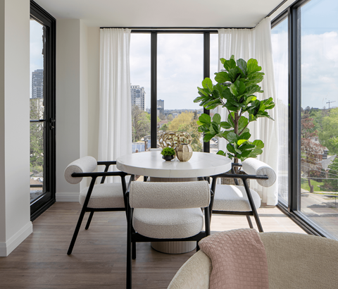 A dining room with a table and chairs and a potted plant.