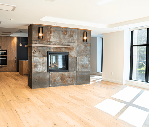 A modern living room with a stone fireplace and wooden floors.