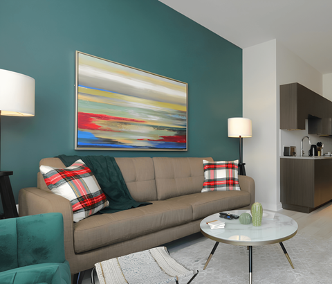 A living room with a couch, a coffee table, and a painting on the wall.