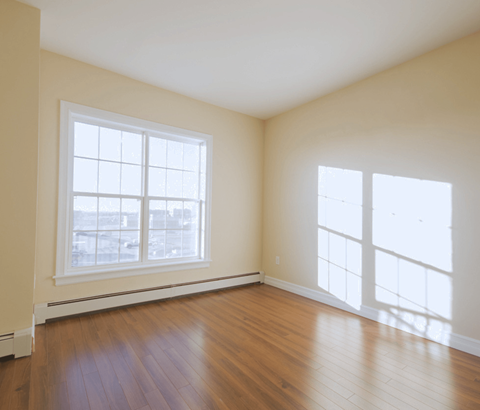 A room with a large window and wooden flooring.